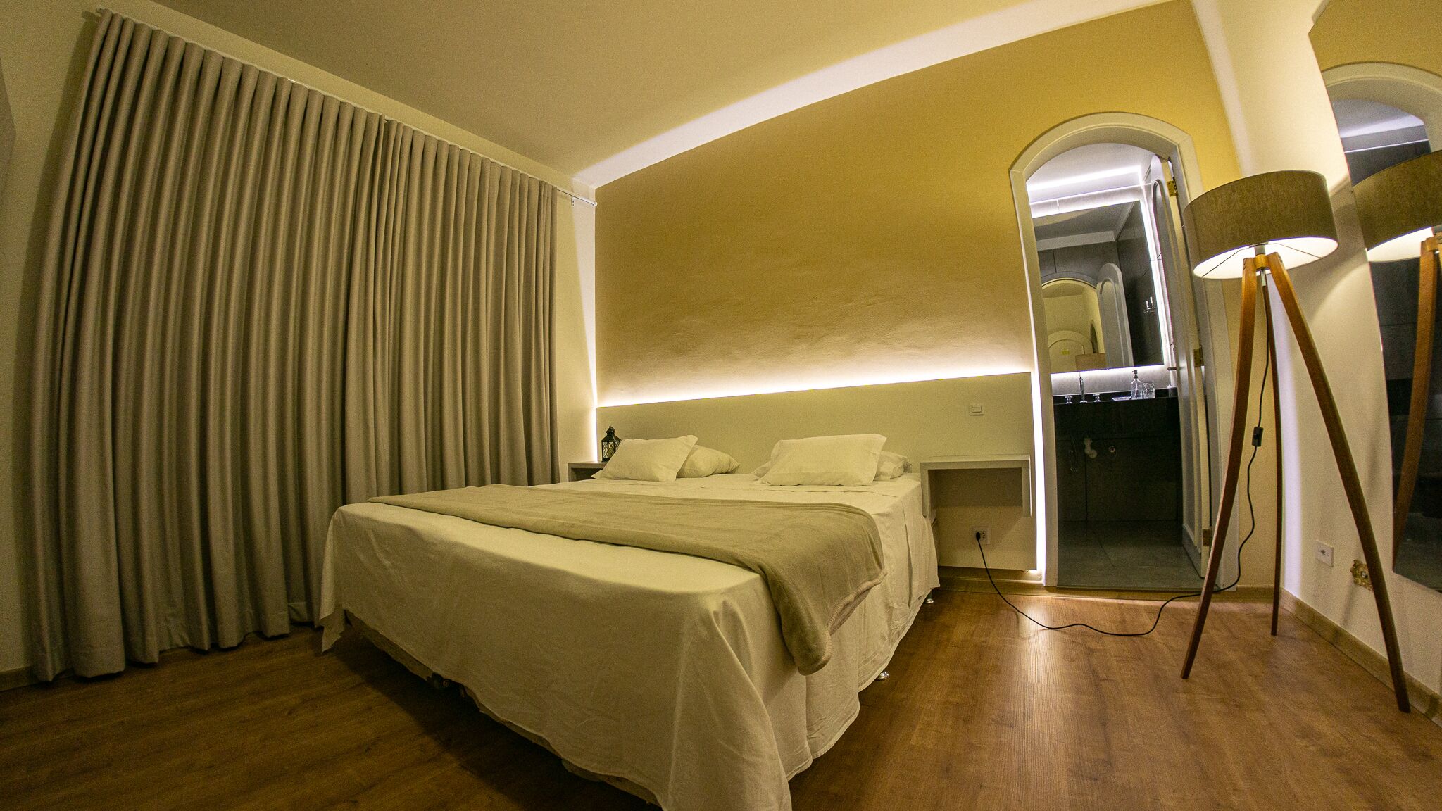 A hotel room with a large bed, a wardrobe, and a mirror.