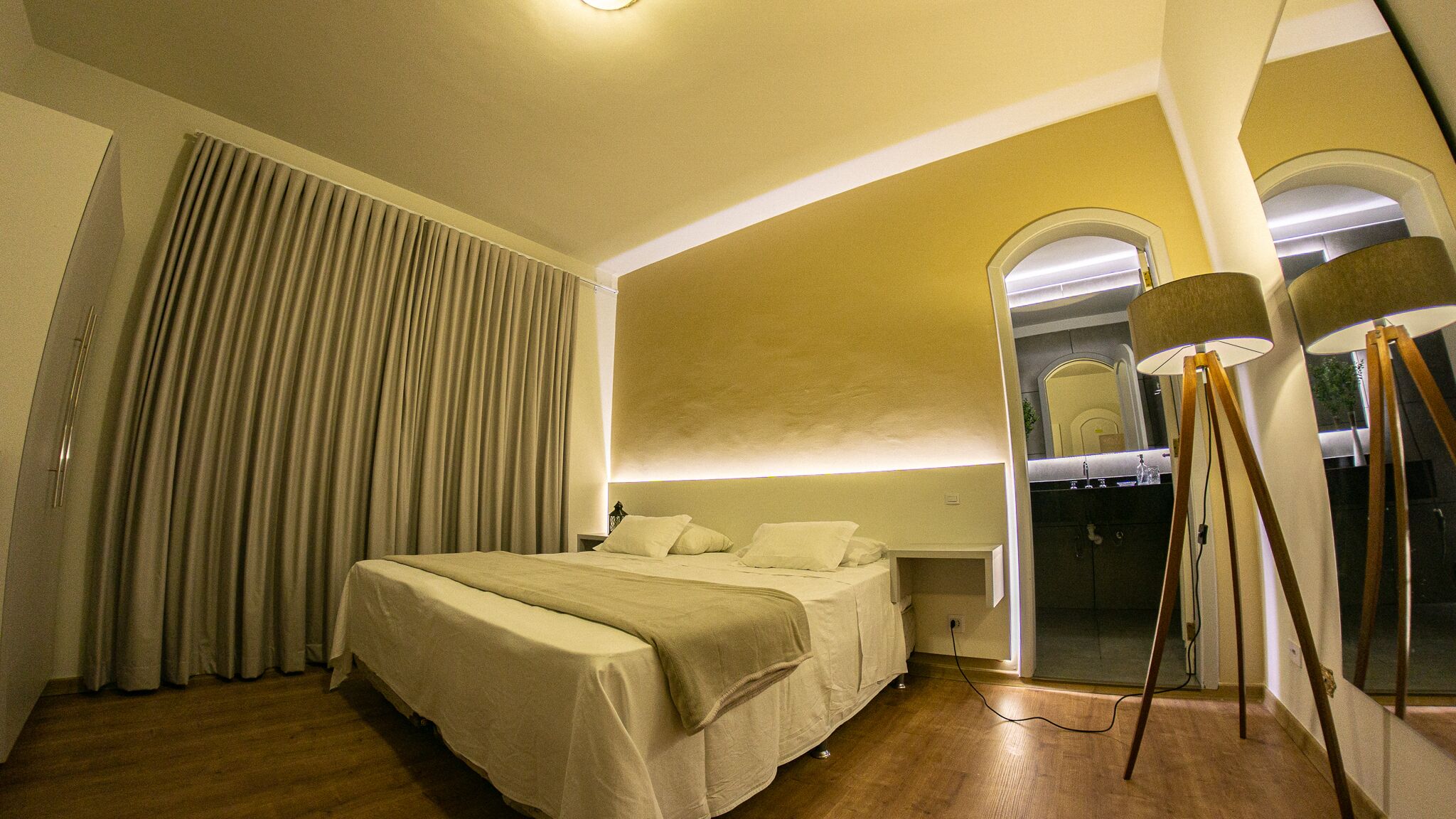 A bedroom with a bed, curtains, and a lamp.