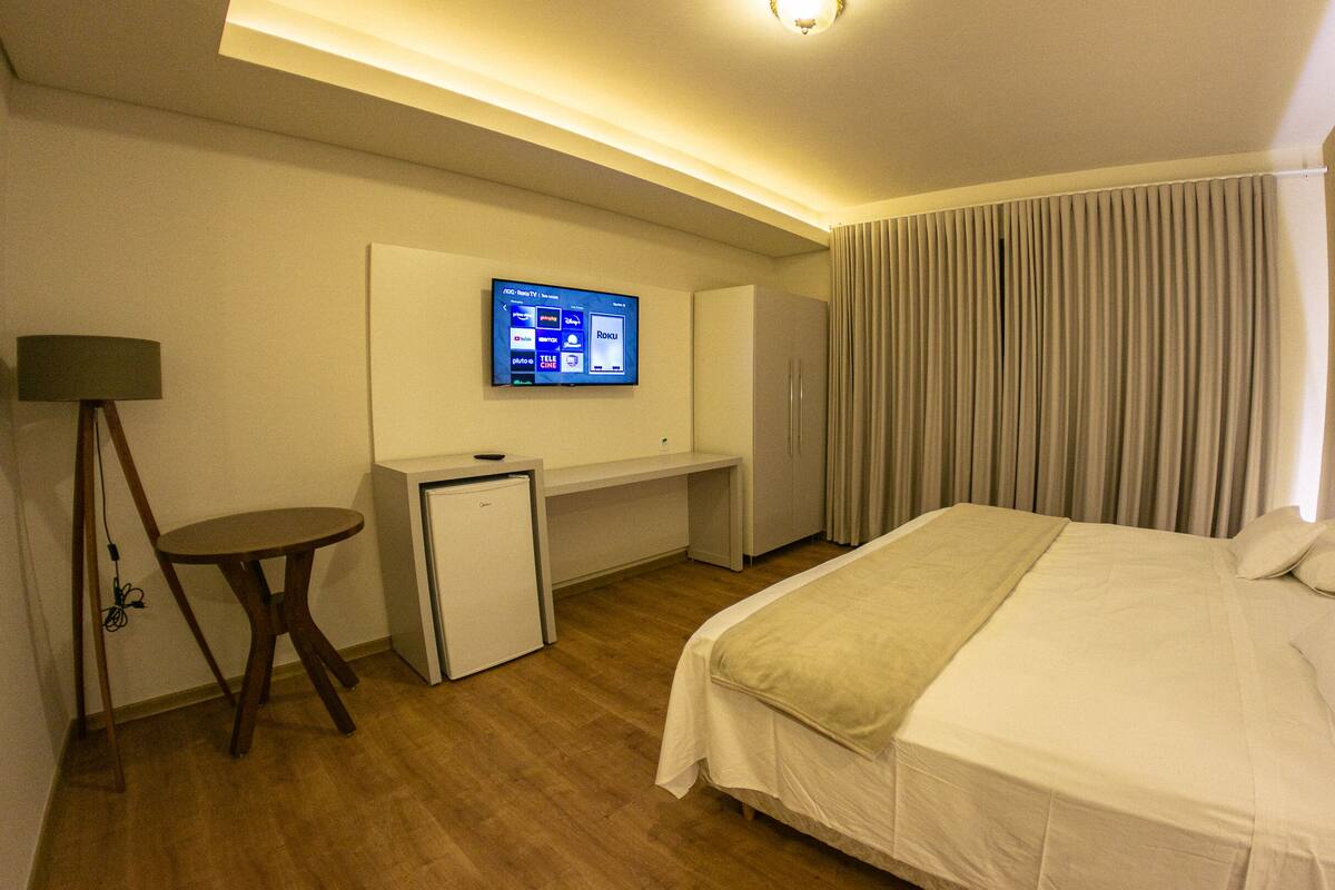 Una habitación de hotel con cama, escritorio, televisor y lámpara.
