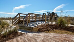 A wooden staircase leading up to a sandy beach area with a clear sky. - Sea Shell 3 Bedroom Townhouse by RedAwning (Navarre)