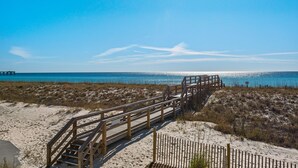 A wooden boardwalk leading to a beach with a pier in the background. - Sea Shell 3 Bedroom Townhouse by RedAwning (Navarre)