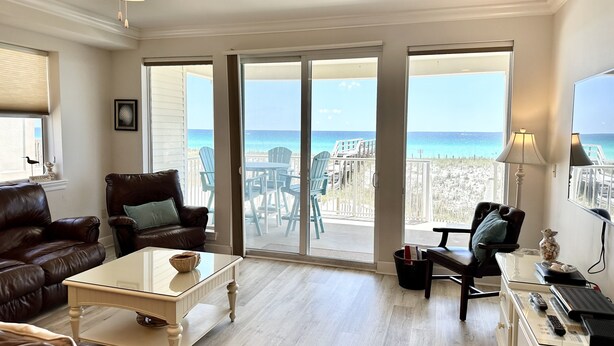 A spacious living room with a view of the beach, a ceiling fan, and a glass coffee table. - Sea Shell 3 Bedroom Townhouse by RedAwning (Navarre)