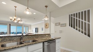 A modern kitchen with granite countertops, stainless steel appliances, and pendant lighting. - Sea Shell 3 Bedroom Townhouse by RedAwning (Navarre)
