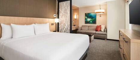 A hotel room with a large bed, a sofa, a TV, and a desk.