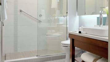 A modern bathroom with a glass-enclosed shower, a white sink, and a wooden vanity.