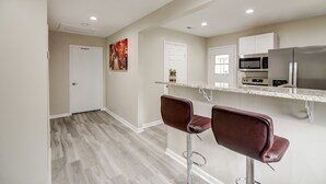 A modern kitchen with a microwave, refrigerator, and bar stools.