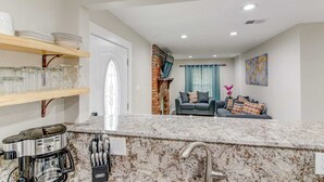 A modern kitchen with granite countertops, a coffee machine, and a knife block.