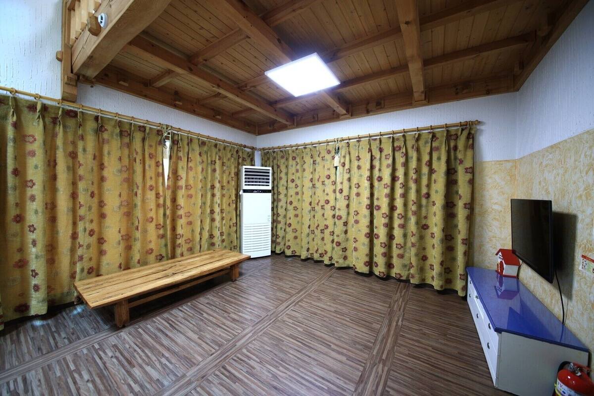 Ein Zimmer mit Holzbalken, einer Bank, einem Flachbildfernseher und einem kleinen Tisch.