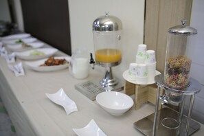 Een buffetopstelling met diverse soorten eten en een sapautomaat.
