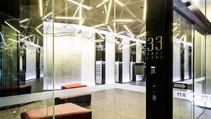 Un intérieur moderne avec des cloisons en verre, un écran numérique indiquant l’étage de l’ascenseur et un espace détente.