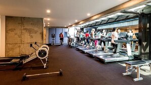 Une salle de sport équipée de tapis de course, de vélos d’appartement et de matériel de musculation.