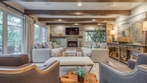 A modern living room with a stone fireplace, large windows, and a cozy seating area.