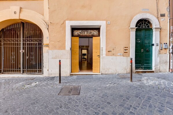 A building with a large arched entrance, a green door, and a barred gate.