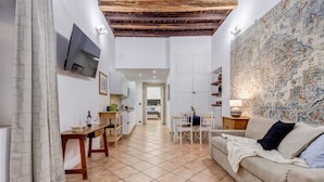 A spacious living area with a sofa, a dining table, and a kitchen in the background. - Coliseum Rome Apartments - Suite (Roma)