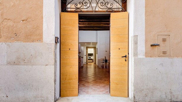 A doorway with a wooden frame and a metal decorative element above it. - Coliseum Rome Apartments - Suite (Roma)