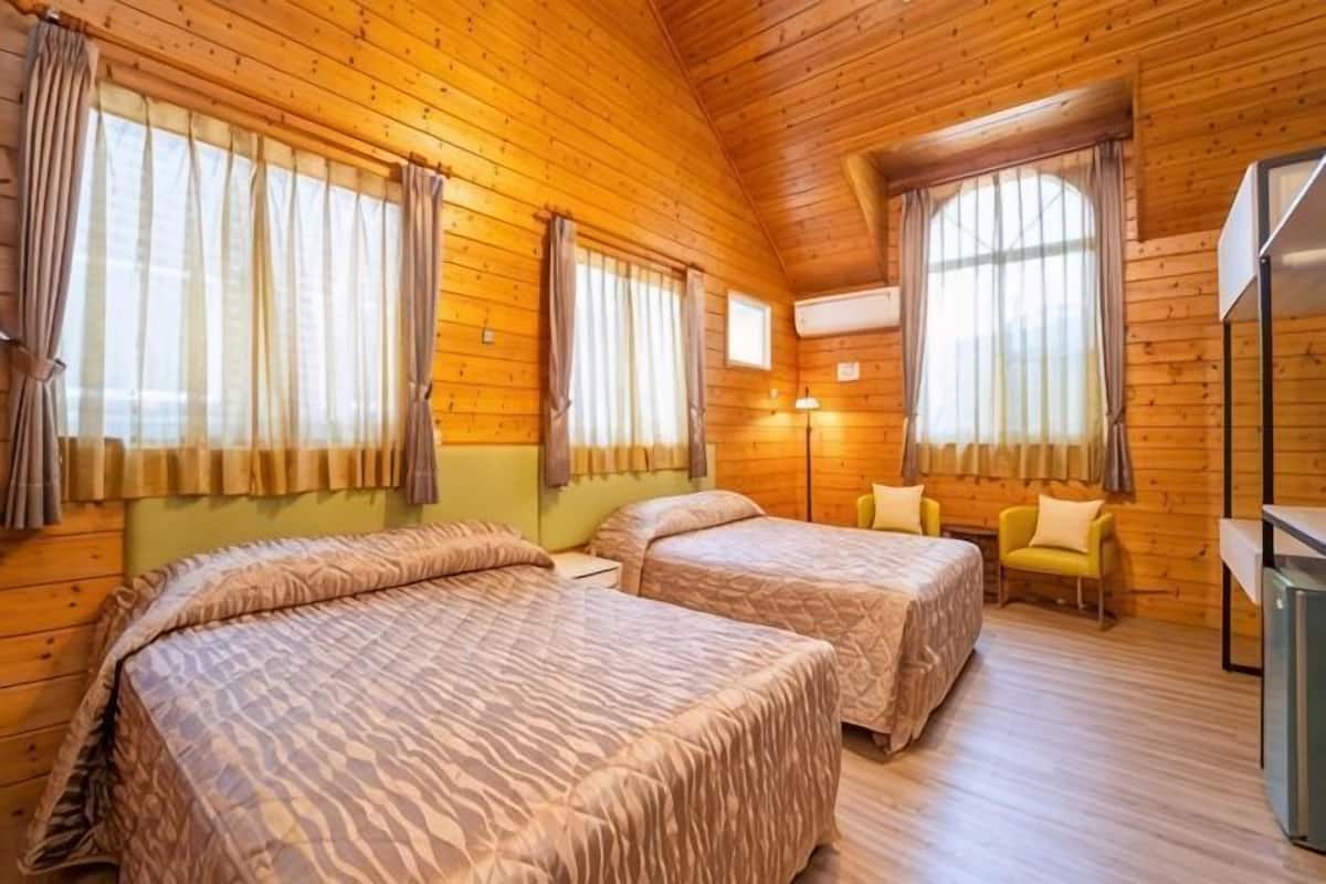 Um quarto em estilo cabana de tronco com duas camas, uma mesinha e um frigorífico.