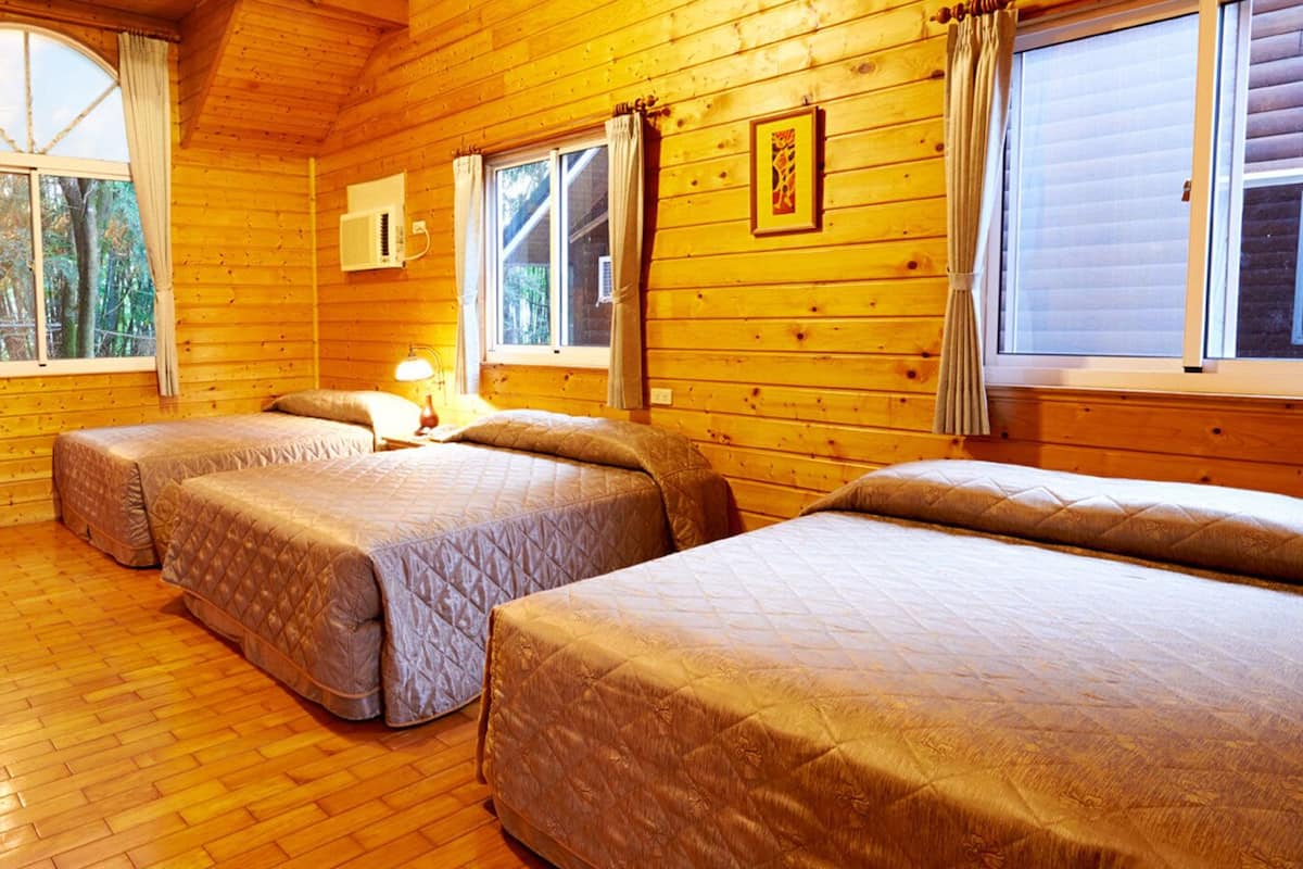 Uma cabana com duas camas, televisão e janela com cortinas.