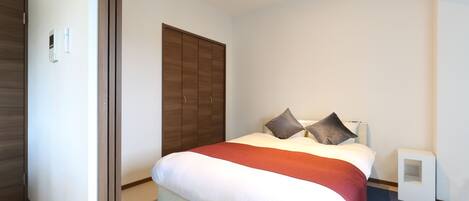 A hotel room with a bed, a wardrobe, and a bedside table.