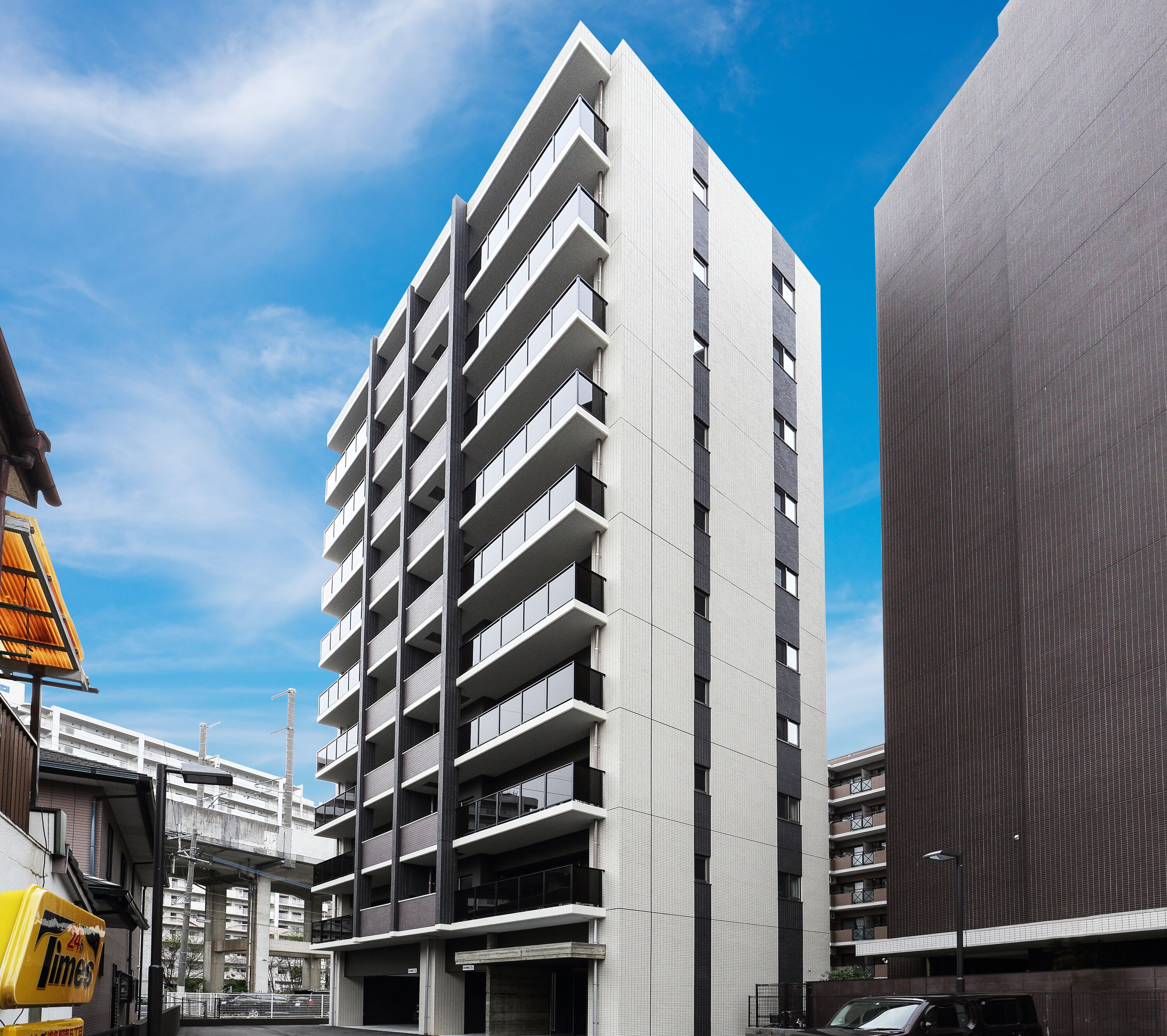 Un immeuble moderne de grande hauteur, doté de nombreux balcons, de grandes fenêtres et d’une façade plane.