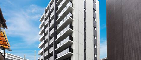 Un immeuble moderne de grande hauteur, doté de nombreux balcons, de grandes fenêtres et d’une façade plane.