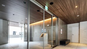 A modern lobby with glass doors, a wooden ceiling, and a bench. - A.T. Hotel Hakata (Fukuoka)