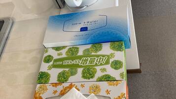 Una encimera con un hervidor eléctrico blanco, una caja de cinta adhesiva y una caja de pañuelos.