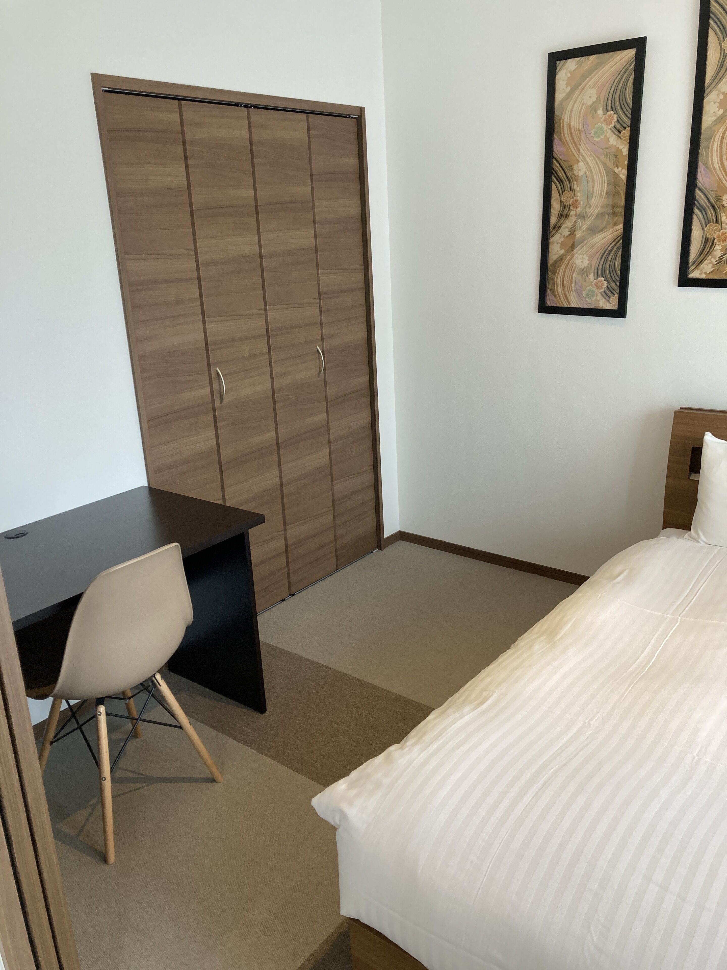 Ein Schlafzimmer mit Bett, Schreibtisch und Kleiderschrank.