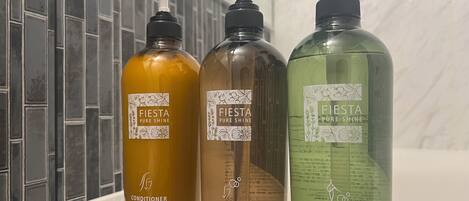 Three bottles of Fiesta Pure Shine products: conditioner, shampoo, and body wash, on a white surface.