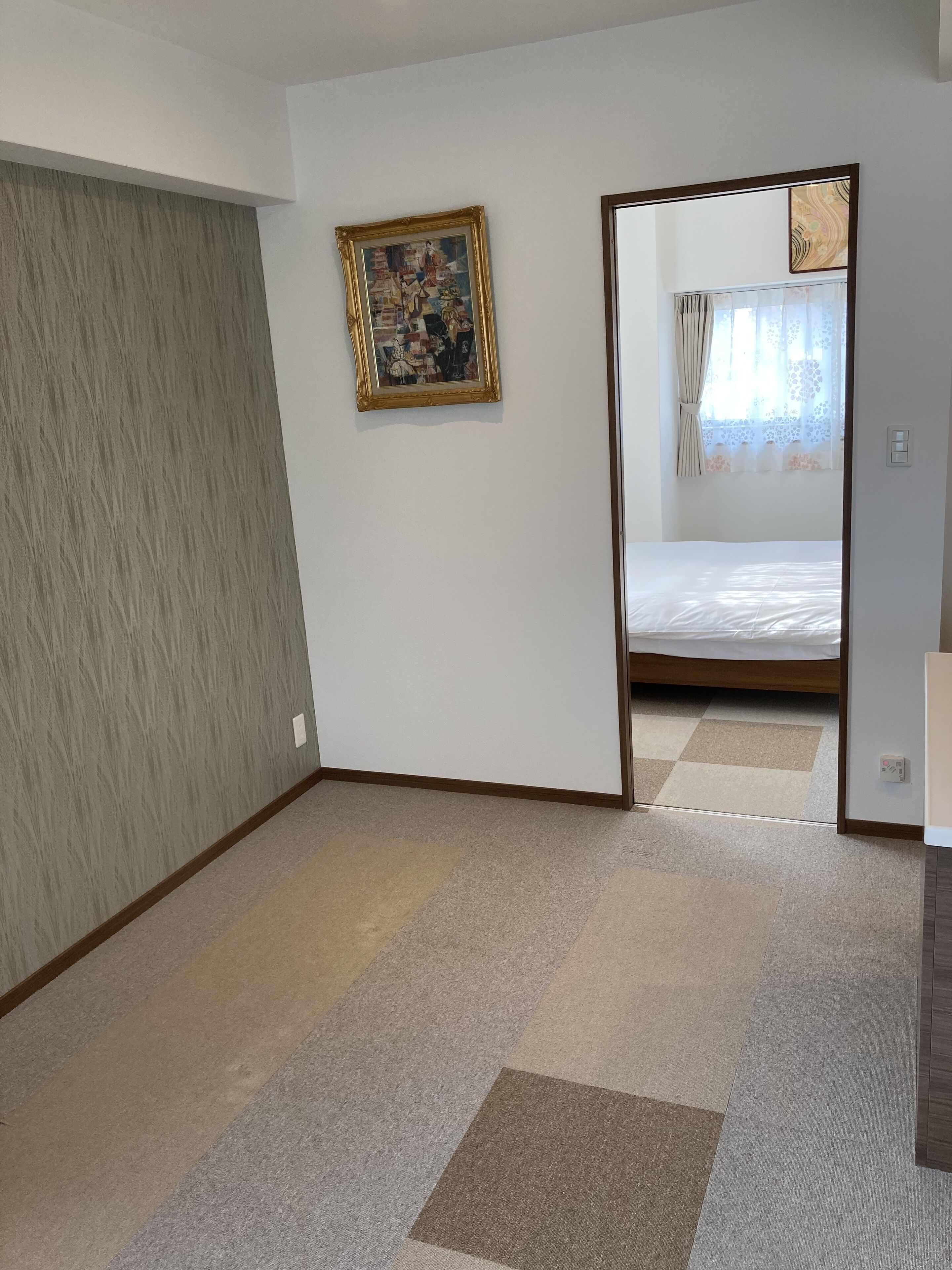 A hotel room with a large mirror, a painting on the wall, and a bed with a white mattress.
