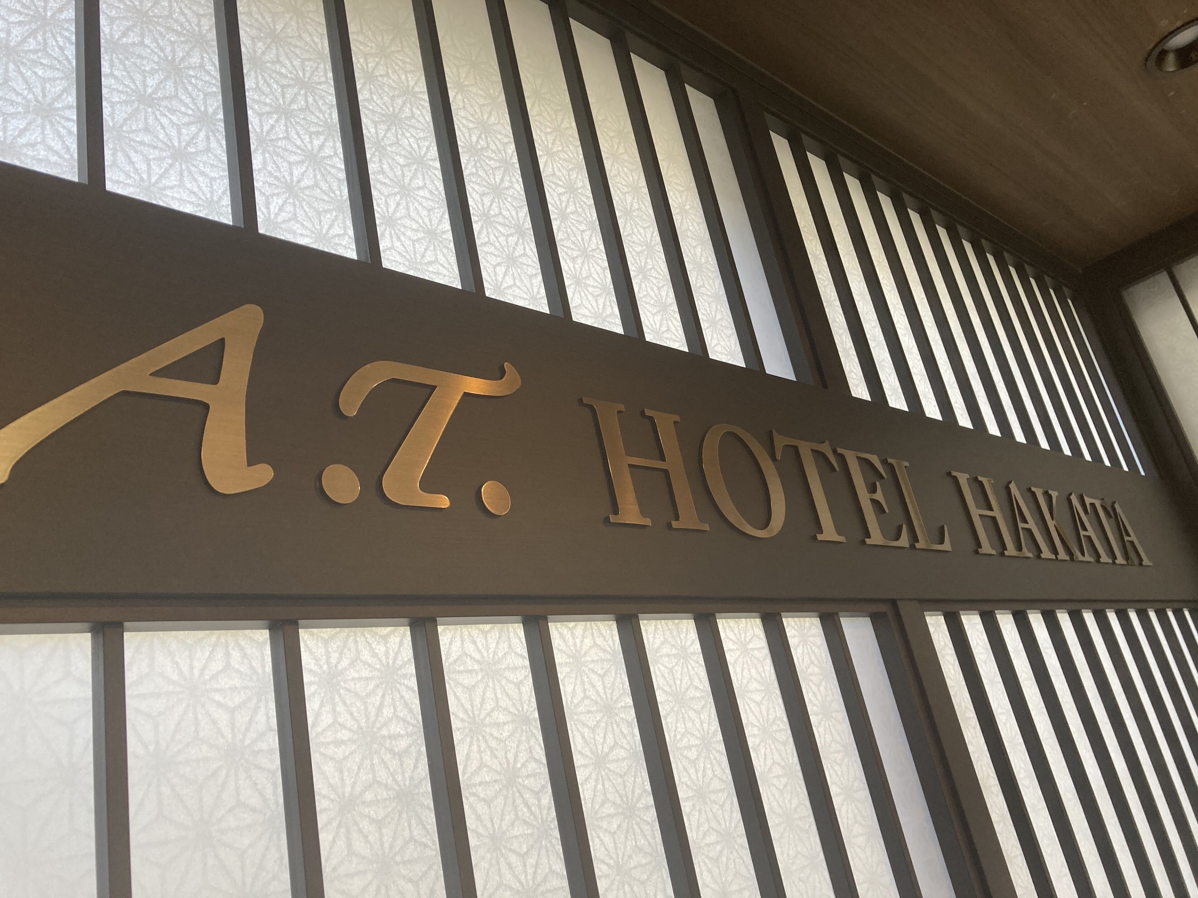 Ein Schild für das A.T. Hotel Hakata mit modernem Design und vertikalen Lamellen.