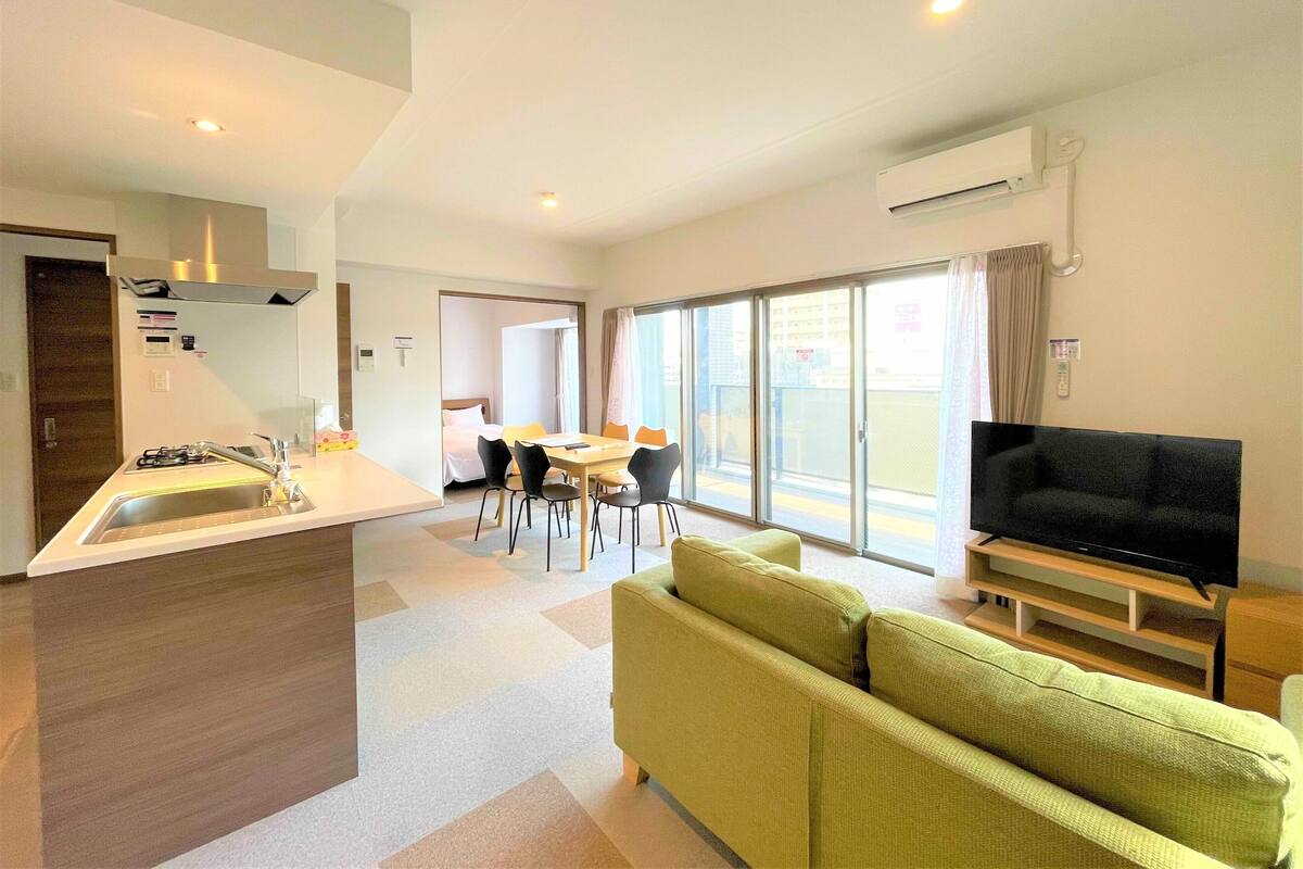 Una habitación de hotel moderna con kitchenette, comedor, sofá y televisión.
