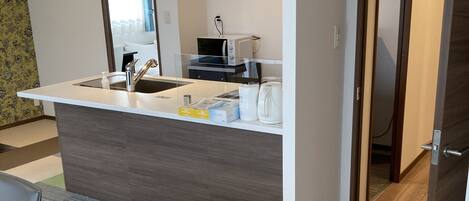 Una cocina moderna con una isla central, microondas y hervidor. Hay una zona de comedor con una mesa y sillas.