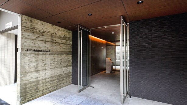 A modern interior with a wooden wall, a glass door, and a dark tiled wall. - A.T. Hotel Hakata (Fukuoka)