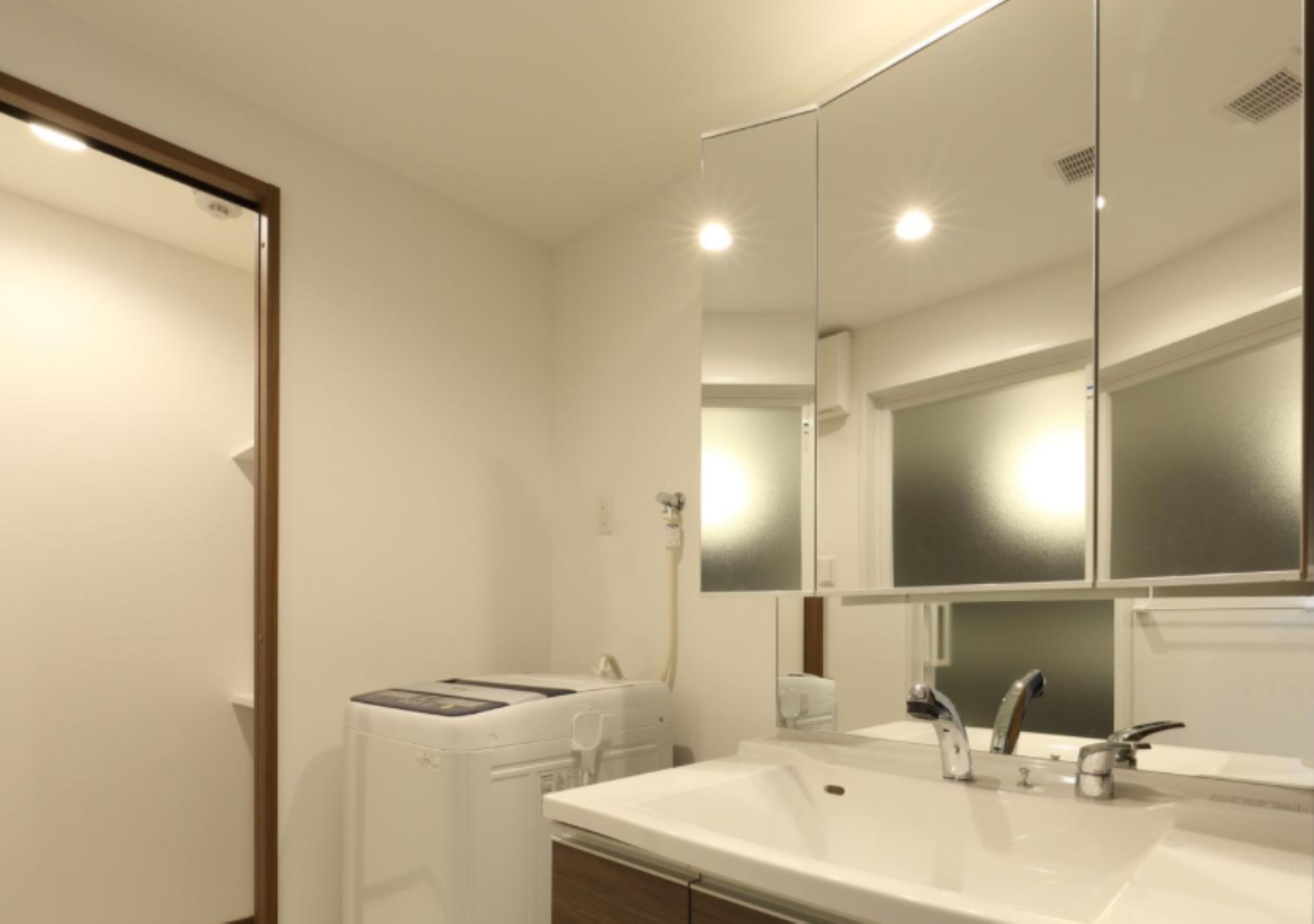 A modern bathroom with a large mirror, a white sink, and a towel rack.