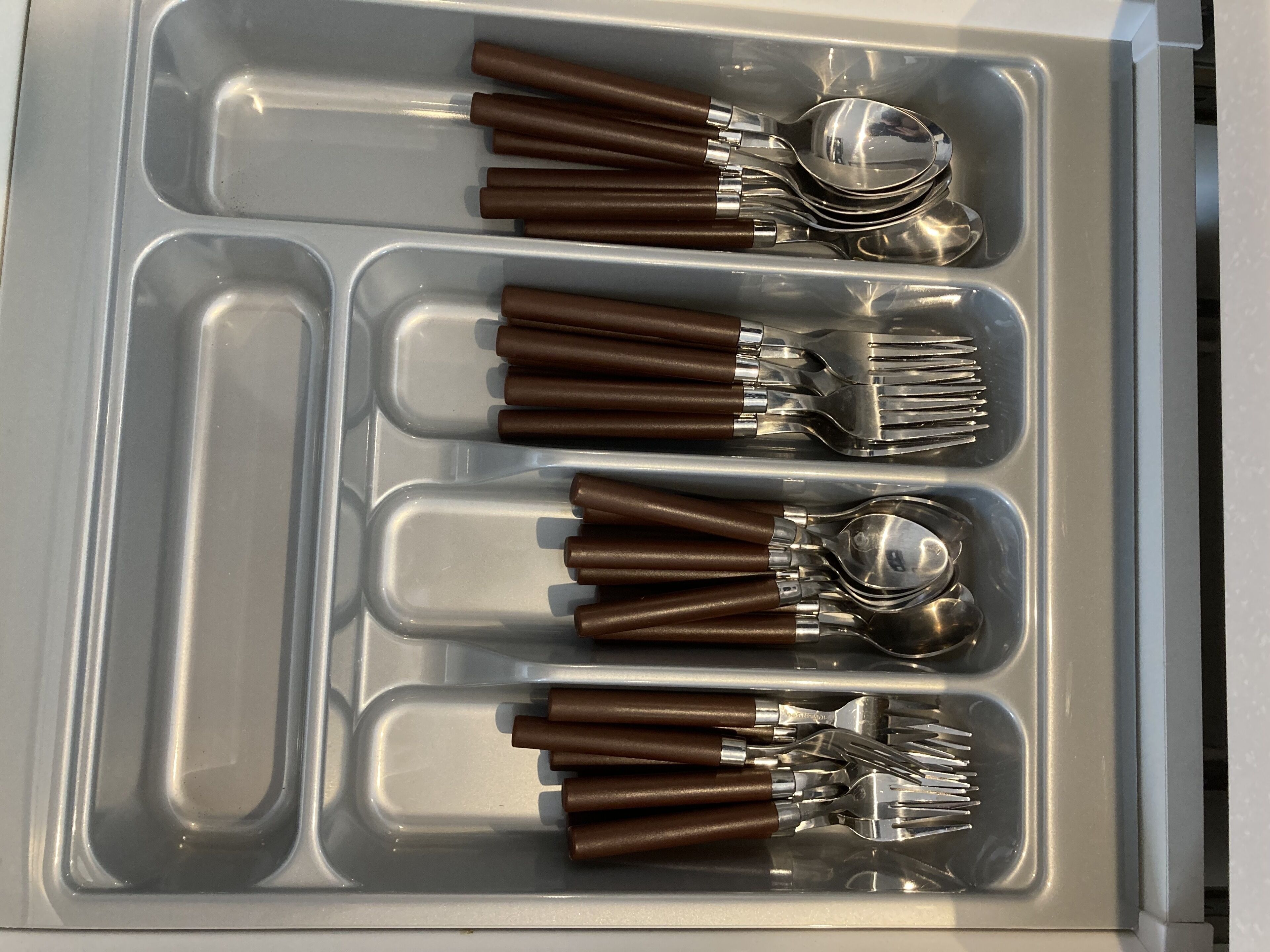 A drawer with compartments containing neatly arranged forks, spoons, and knives.