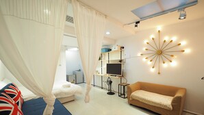 A bedroom with a bed, a sofa, a TV, and a wall-mounted light fixture. - Near StayReal Location (Taipei)