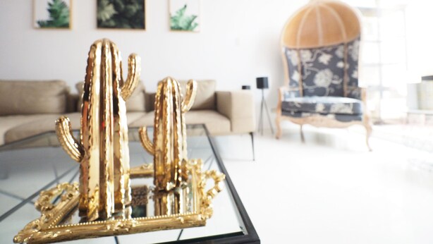 A living room with a glass coffee table displaying a golden cactus sculpture. There is a sofa and a chair in the background. - Near StayReal Location (Taipei)