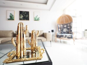 A living room with a glass coffee table displaying a golden cactus sculpture. There is a sofa and a chair in the background. - Near StayReal Location (Taipei)