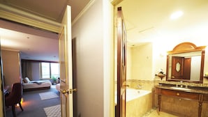 Une chambre d’hôtel comprenant un lit, un bureau et une salle de bain avec une baignoire et un miroir.