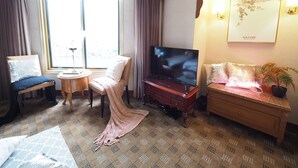 Une chambre d’hôtel dotée d’une grande fenêtre, d’un téléviseur, d’une petite table ronde, d’un canapé et d’un élément décoratif mural.