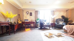 Une chambre d’hôtel avec un piano, un coin salon, un canapé confortable et un lit.