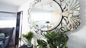 A room with a large ornate mirror, a sofa with a cushion, and a potted plant. - Yongchun MRT Station (Taipei)