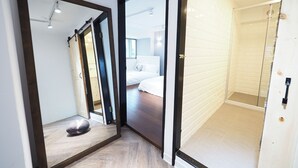 A modern bathroom with a glass shower enclosure, a wooden floor, and a white bathtub. - Yongchun MRT Station (Taipei)