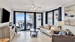 Un salon moderne doté d’un téléviseur à écran plat, d’un canapé, d’une table basse et d’un balcon offrant une vue sur la mer.