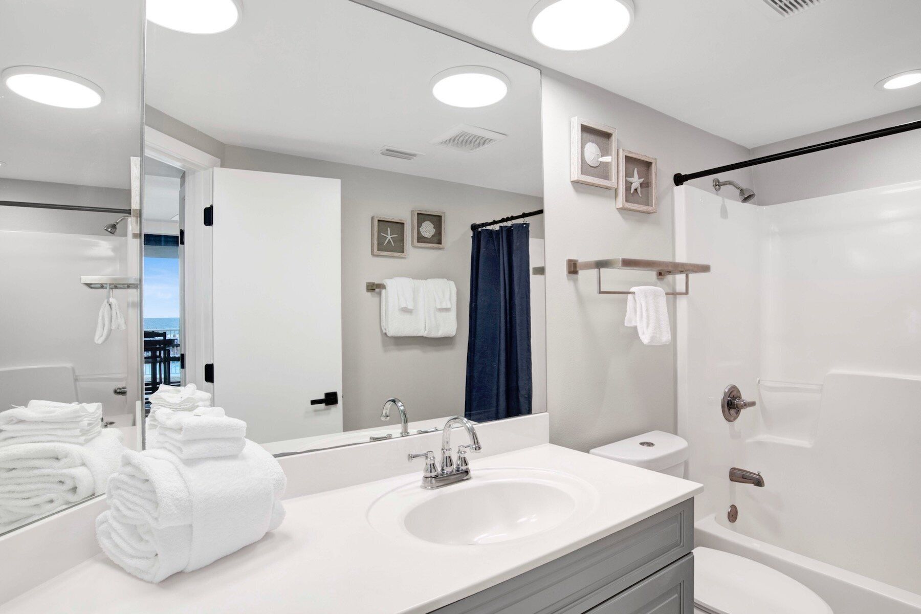 Une salle de bain moderne avec un lavabo blanc, un grand miroir et une douche.