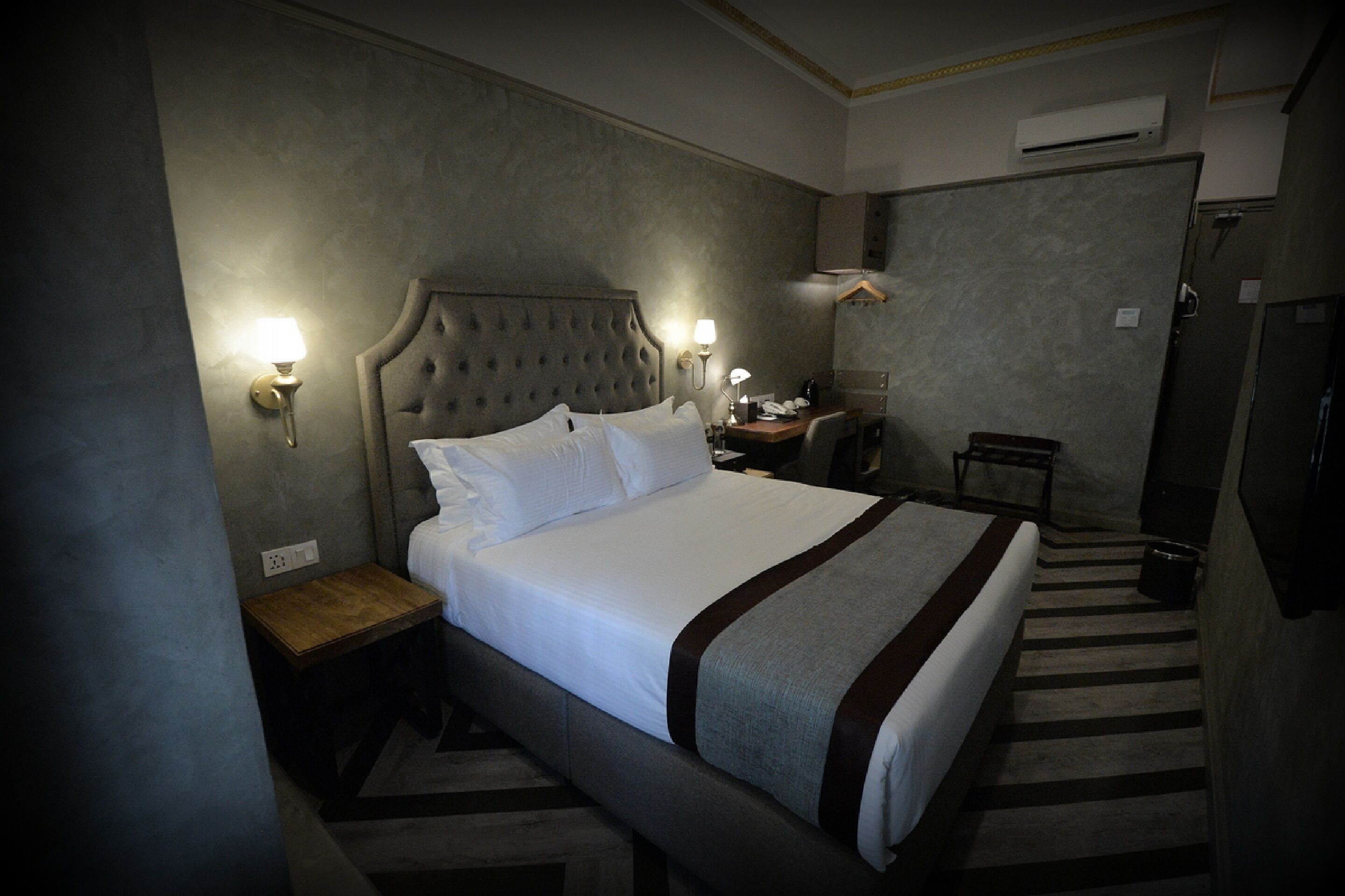 Habitación de hotel con una cama grande, dos mesitas de noche, un escritorio y una silla.