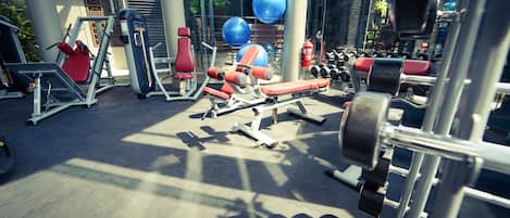 Un gimnasio con diversos equipos de ejercicio, incluyendo cintas de correr, máquinas de pesas y pesas libres.