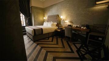 A hotel room with a large bed, a desk with a chair, a lamp, and a telephone.