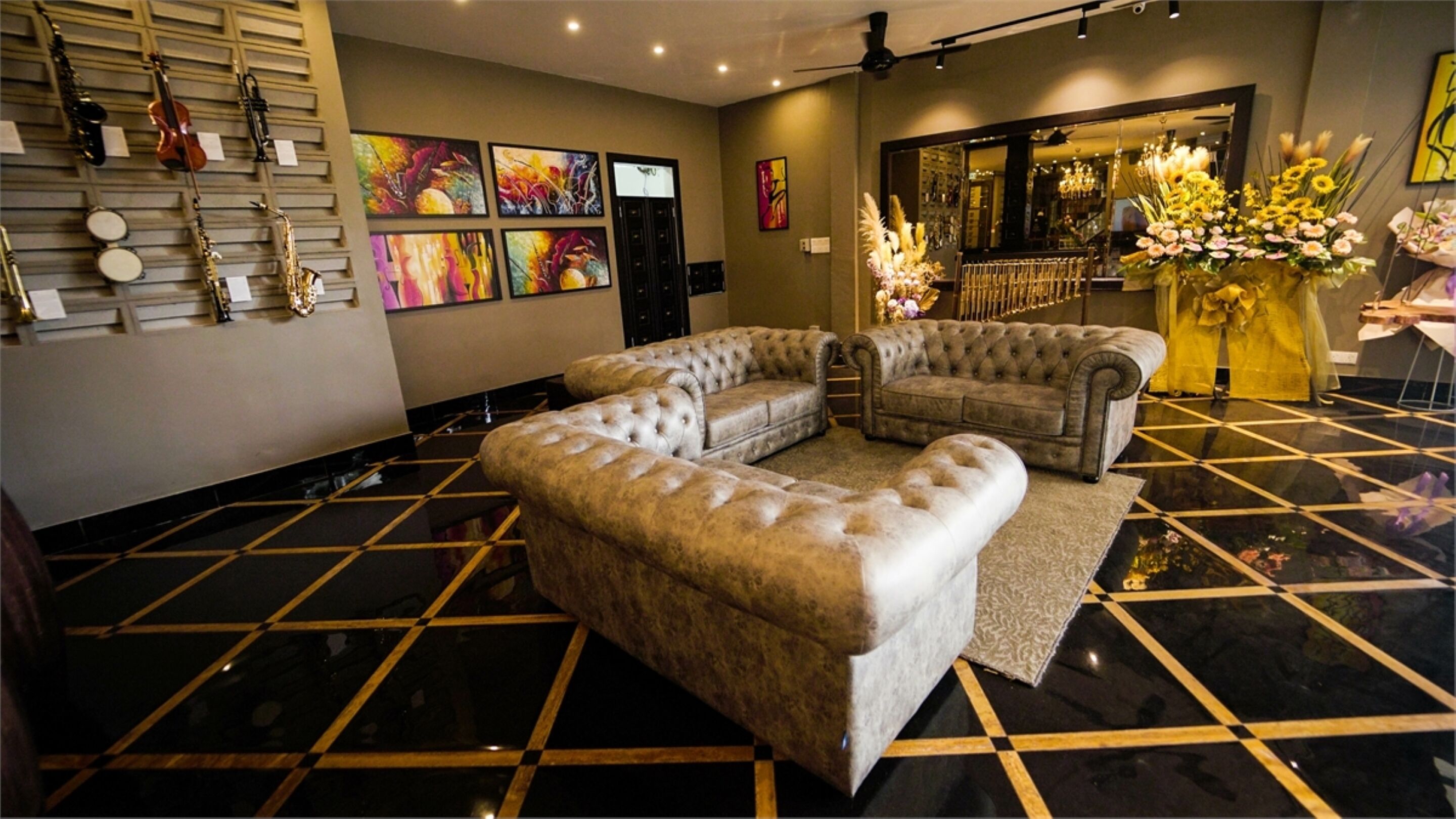A lobby with a black and gold checkered floor, two tufted sofas, a wall-mounted violin rack, and colorful artwork.