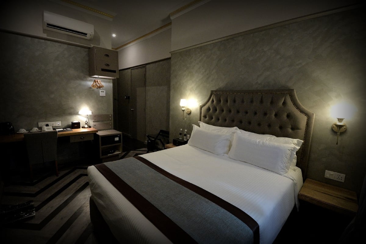 Ein Hotelzimmer mit einem großen Bett, einem Schreibtisch mit Stuhl, einem Kleiderschrank und einem Spiegel.